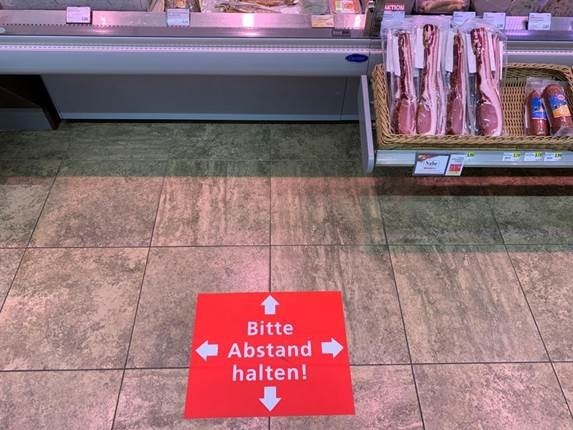 Bild zeigt Abstandshinweis vor einer Feinkosttheke in Form einer Bodenmarkierung